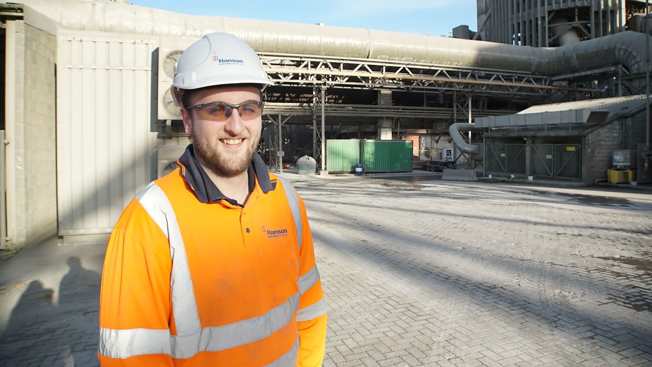 Alex at work, smiling to camera.