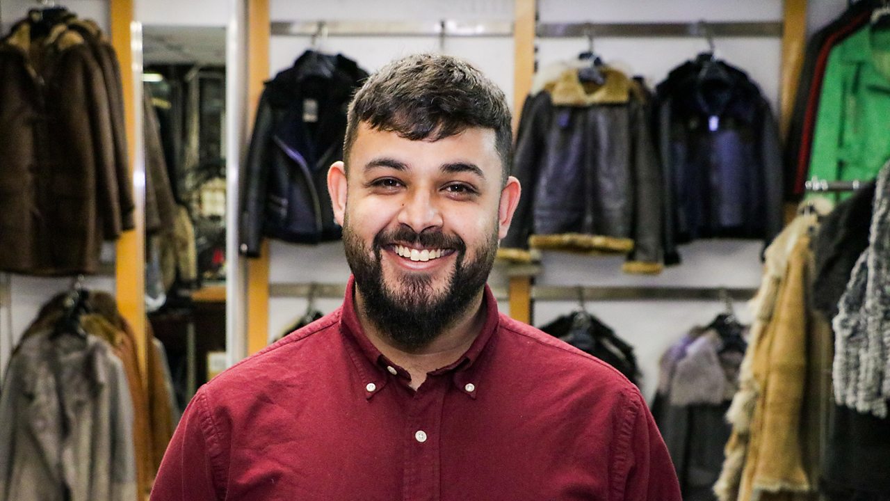 Wasim in the shop, smiling at the camera.