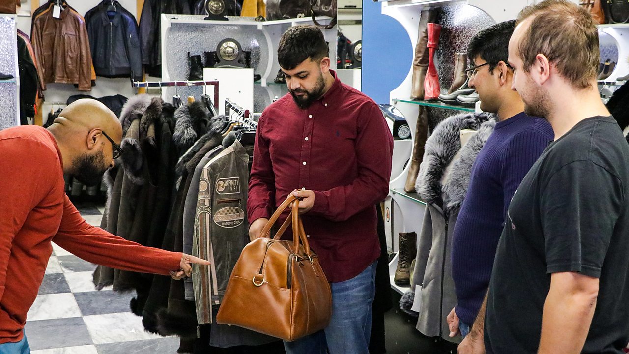 Wasim and his colleagues, looking at one of their products – a brown leather bag.