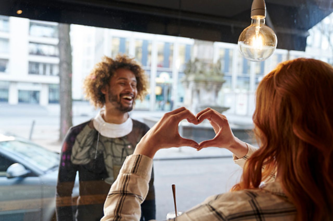 Woman making heart through window