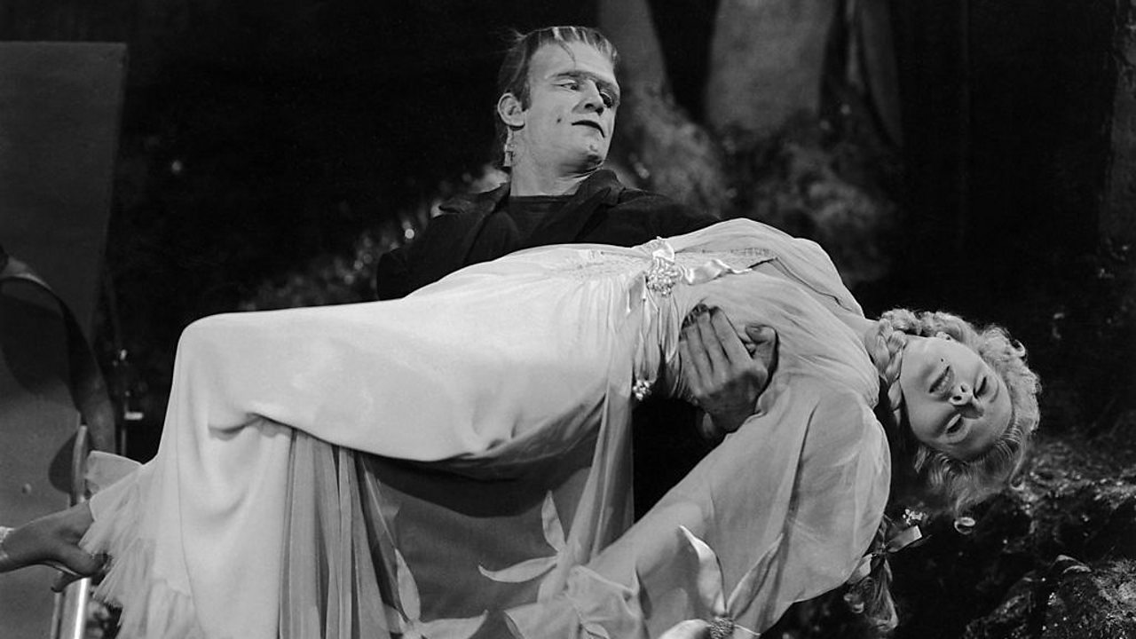 Frankenstein's monster holds a fainted damsel in his arms.
