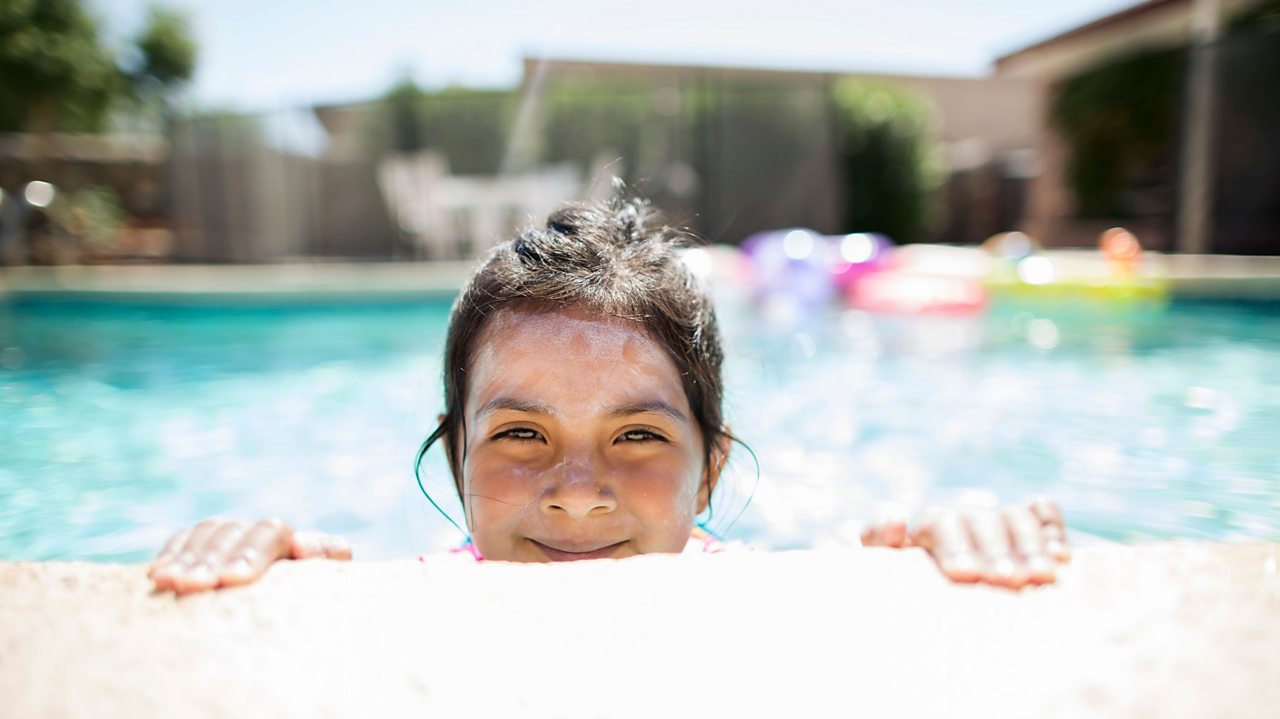 Girl in swimming pool with sunscreen on her face.