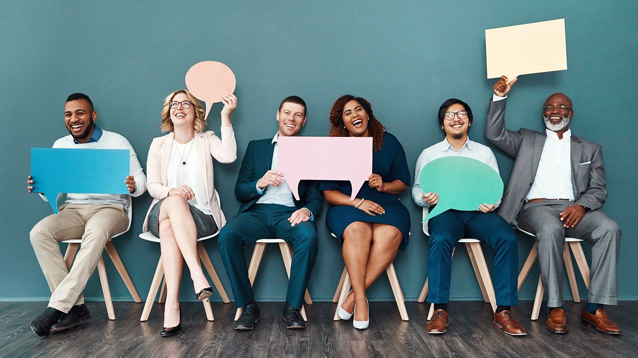 A diverse group of six people hold up paper speech bubbles of varying shapes and sizes.