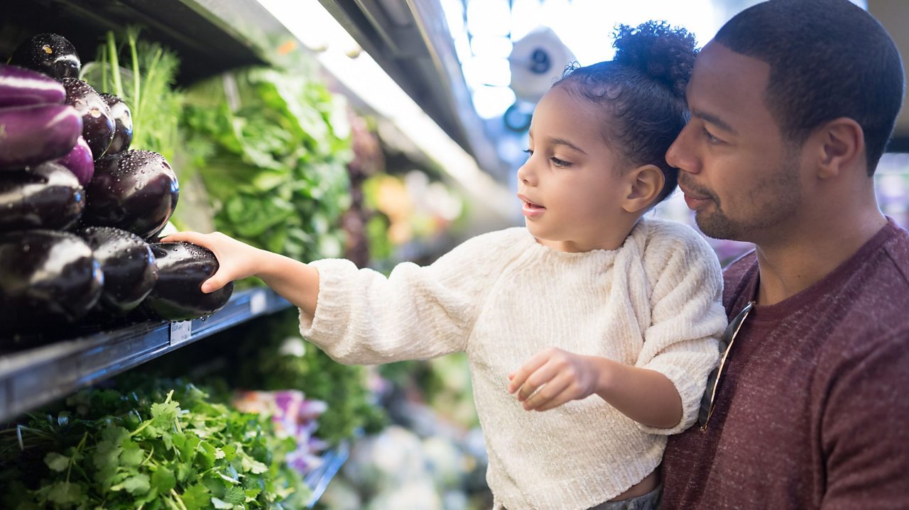 Child picking vegetables at supermarket