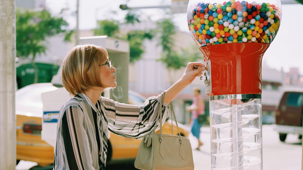A woman using a gumball machine.