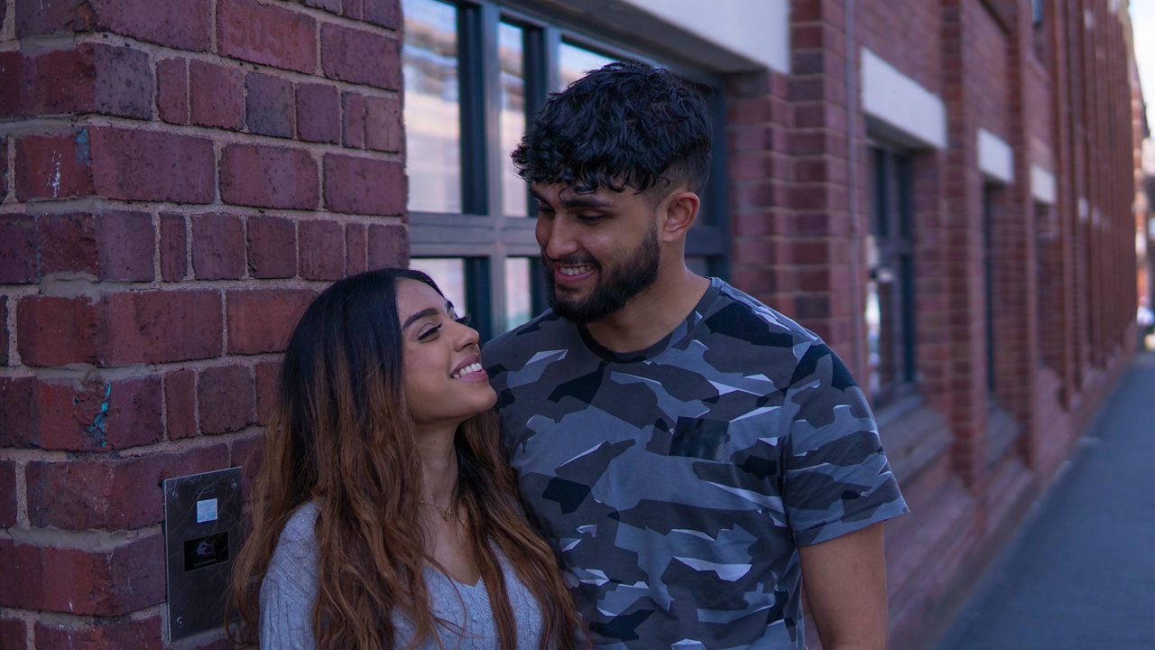 Tanya and Ryhan smiling at each other outside their property
