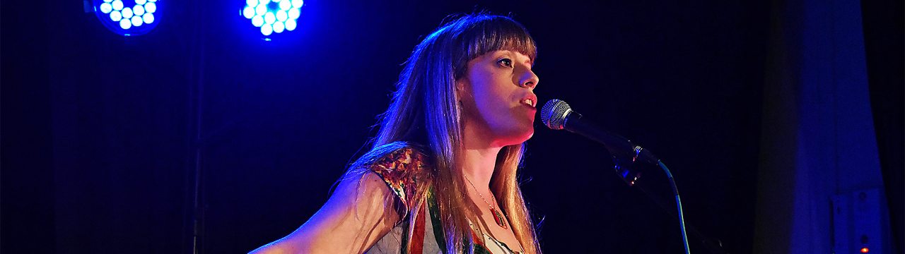 Somerset poet Liv Torc on stage in front of a microphone
