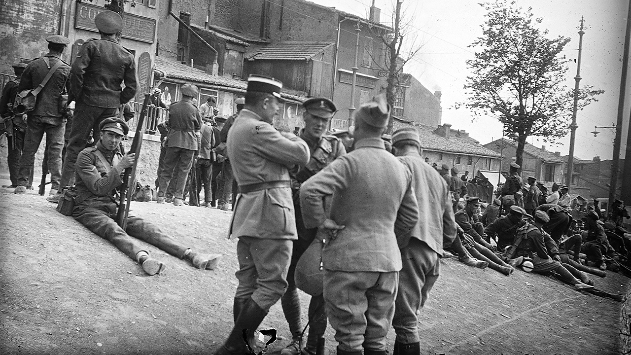 White officers stood and sat in a town during World War One.