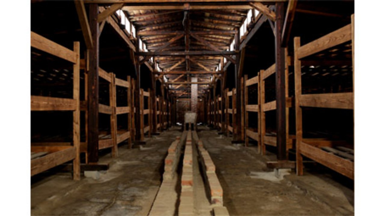 A photograph of wooden bunks in a dormitory at Auschwitz.