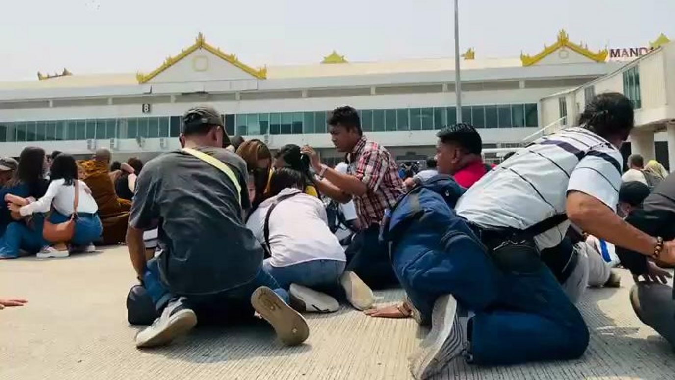 People crouch on the tarmac in Mandalay airport