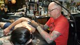 Tattoo artist Alex Binnie working on a client, Stefano