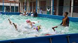Children learning to swim in a portable pool at a school in Dhaka