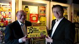 Robert Opie and Jonathan Freedland at the Museum of Brands, Packaging and Advertising with an advert for Bile Beans