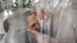 People hugging through a plastic sheet in room in Italian care home in November 2020 (Credit: Max Cavallari)