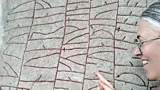 A triangular shaped stone with carvings including runic writing in a field (Credit: Magnus Källström, the Swedish National Heritage Board)
