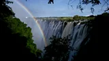 A rainbow-like lunar rainbow arcs through the mist in front of Victoria Falls at night (Credit: Sarah Steger)