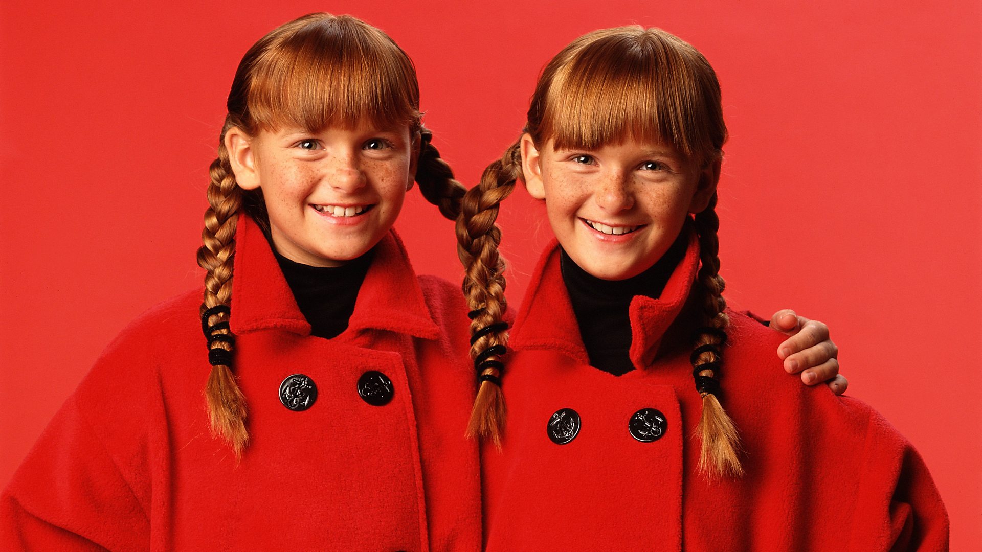 Twin girls wearing matching coats and pigtails (Credit: Jade Albert Studio, Inc via Getty Images)