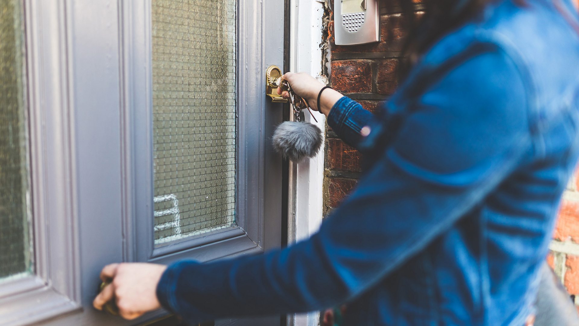 Woman opening a flat's front door with some keys