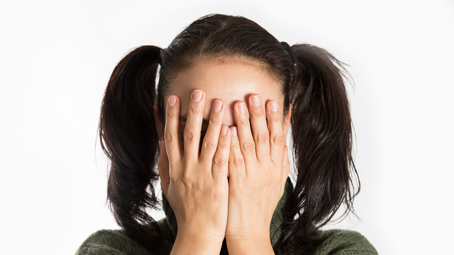 Girl in pigtails covering her eyes with her hands