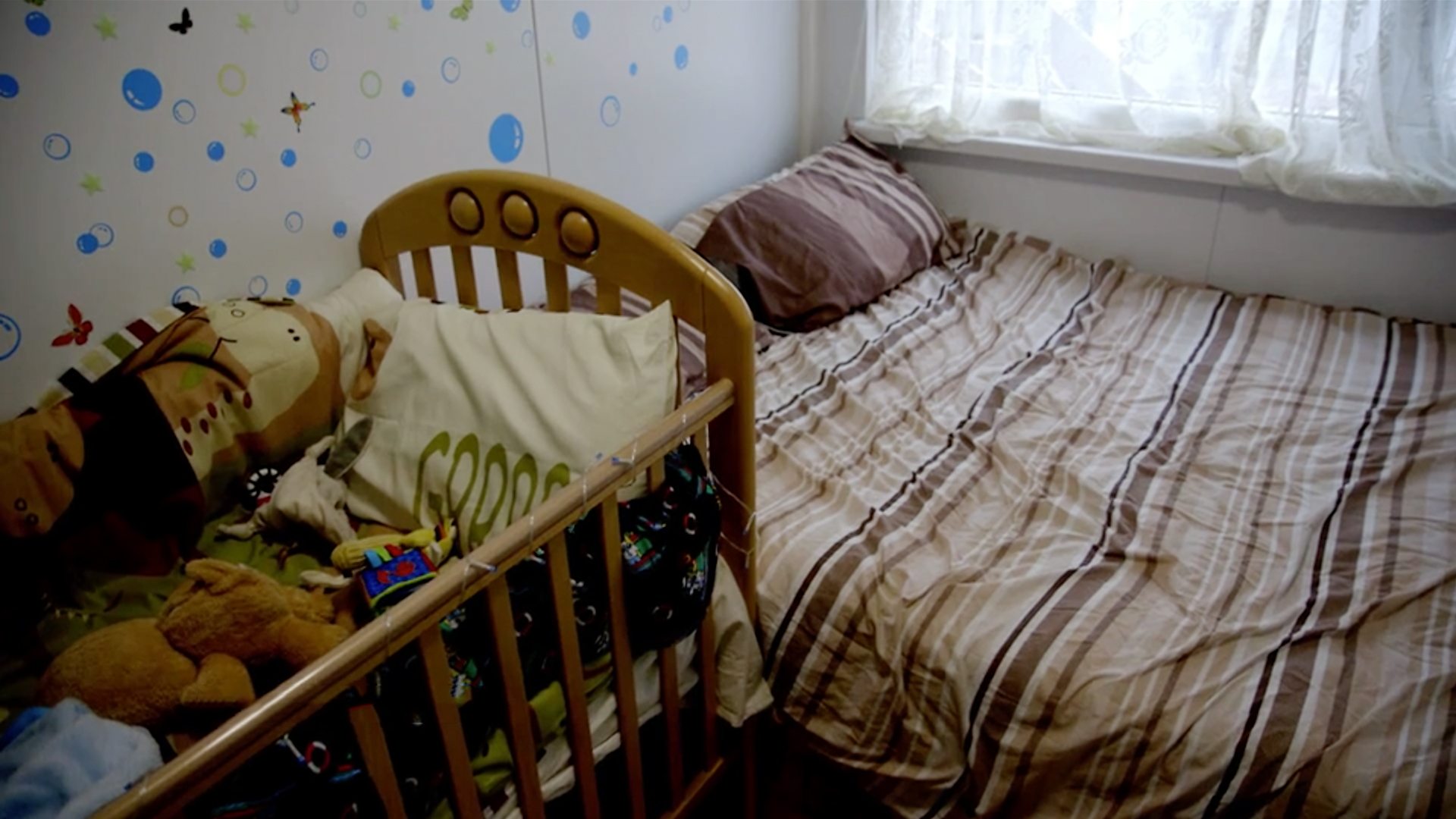 Photo of the interior, showing her bed and a baby's cot pushed right up against one another