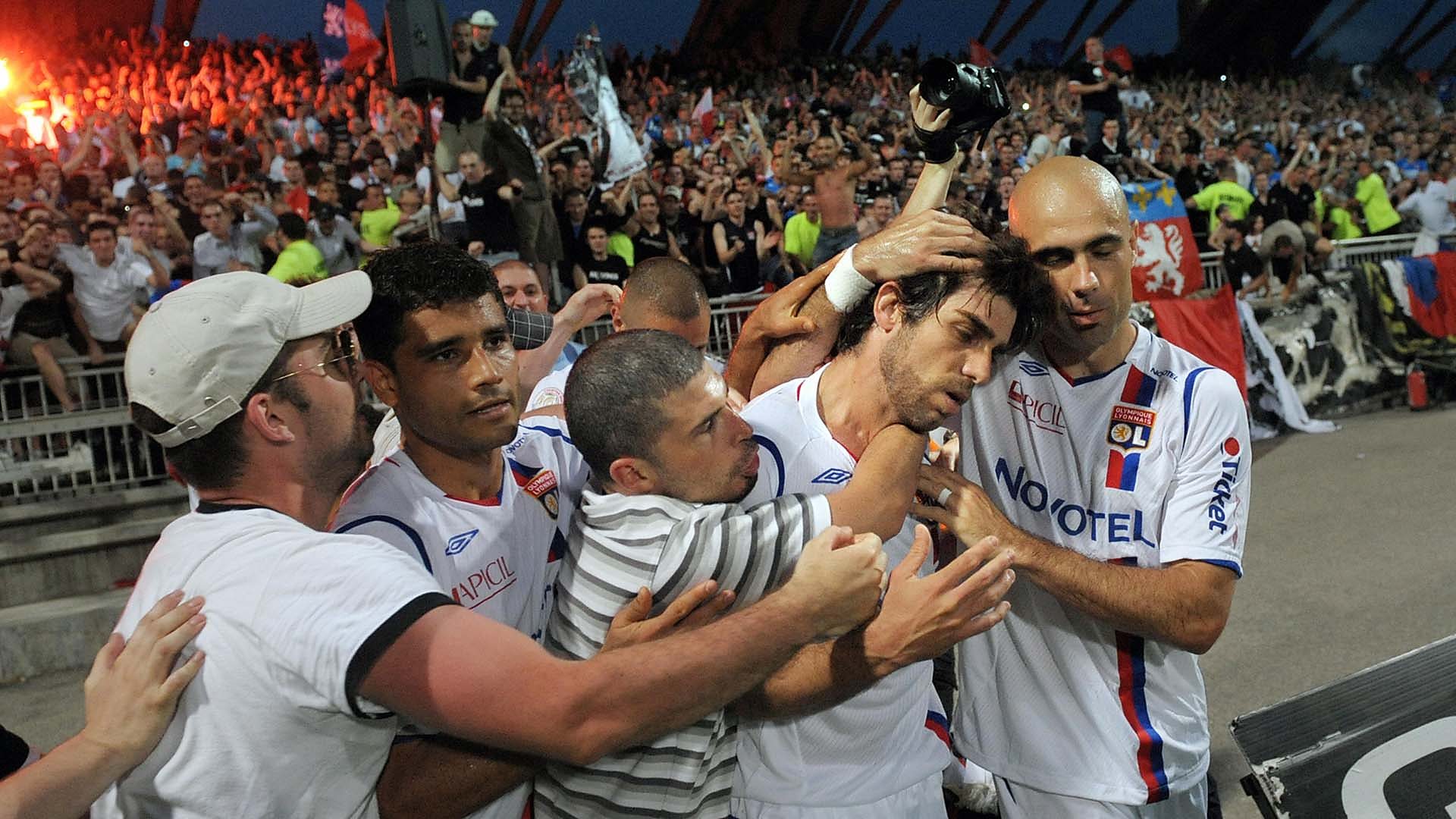 Juninho is mobbed by Lyon fans and team-mates