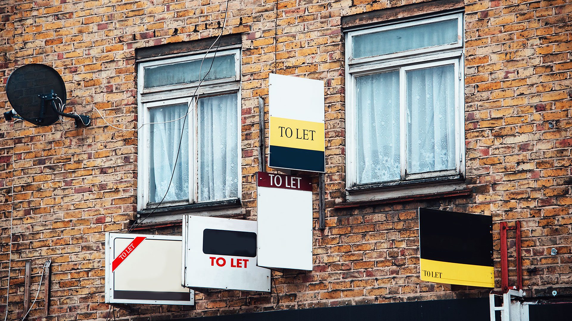 Multiple To Let signs on the wall of a block of flats