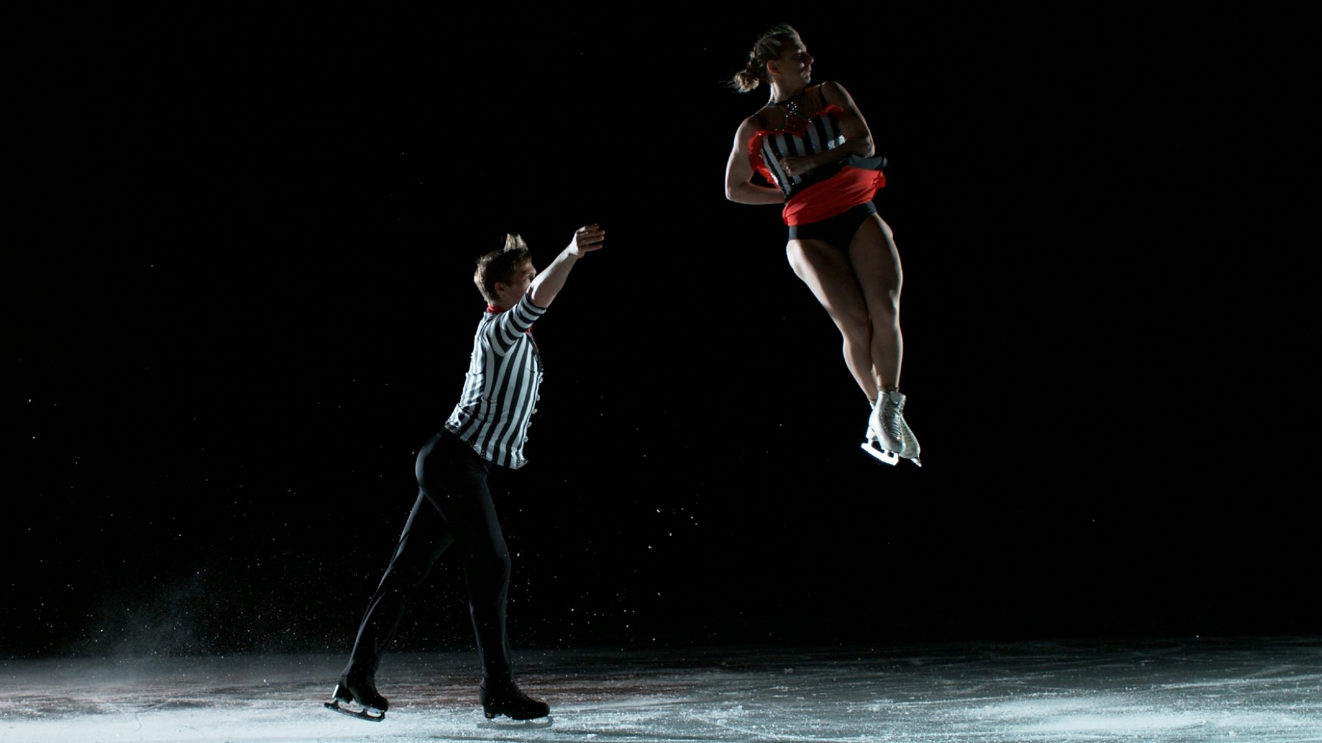 A dramatic image of a male skater, Harry, throwing his pairs partner, Lydia, on the ice. Captured as she is mid twist in the air.