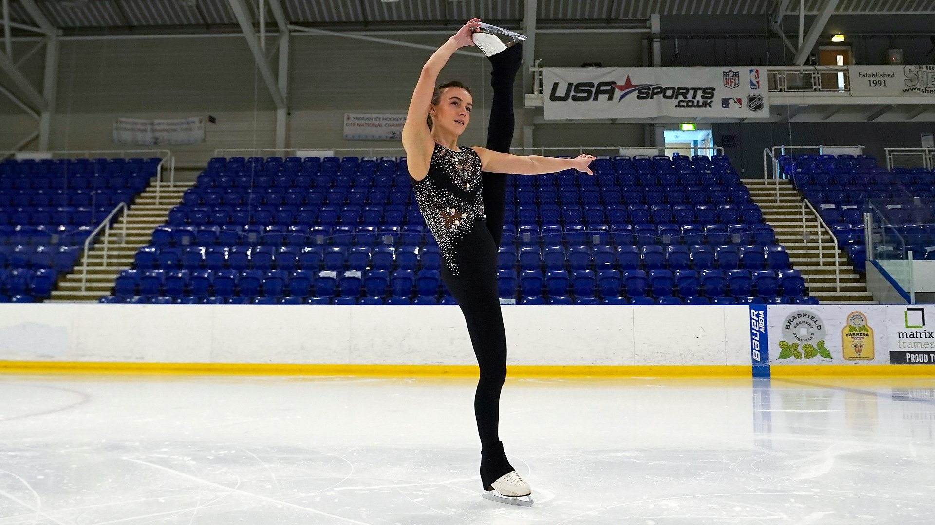 Emily doing a trick on the ice, holding her leg up above her head