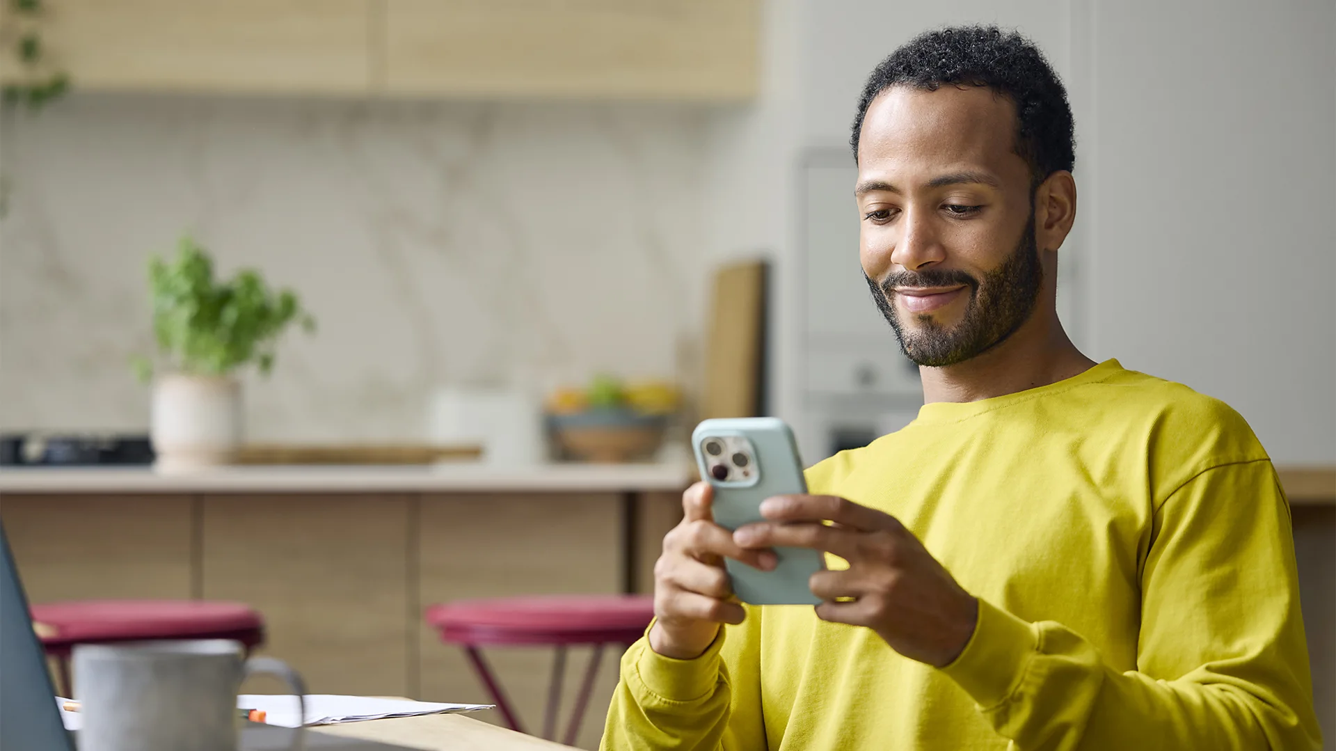 Getty Images A man sits staring at his phone and smiles at it (Credit: Getty Images)