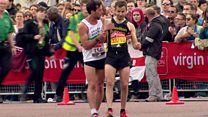 Exhausted marathon runner helped across line