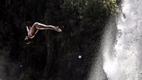 Divers leap before stunning waterfall