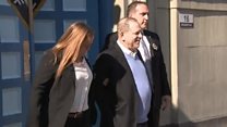 Harvey Weinstein smiles in handcuffs