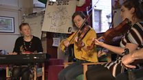 Luchd-ciùil a' tadhail air dachaighean cùraim