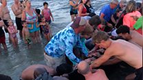 Beachgoers come together to help stranded whales