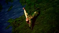 Dancers perform suspended from building
