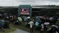 Umbrellas are raised on Henman Hill