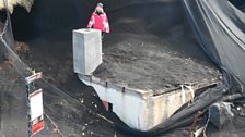 Kate stands on the roof of an ash-covered house