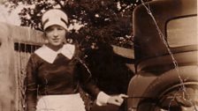 A 1920's servant posing in front of a car