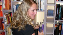 Rachel checks the bookshelf for surveillance devices - you can't be too careful these days.