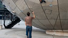 Aled takes a photo of himself at our second location - the waterfront. Here he is reflected in a big ball...