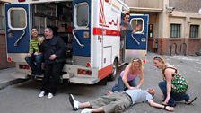 Paramedics Carrie and Rachel tend to an emergency while their colleagues look on all concerned.