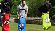 And they're off! Dom, Aled and Vernon get jumping in the sack race. There's just one snag - the sacks are kid-sized!