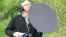 Chris Watson recording with a parabolic reflector on a path through the woodland