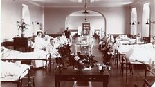 A Nursing Sister from the Queen Alexandra’s Royal Naval Nursing Service, with other Sick Berth staff and, seeing to patients