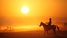 Omani man on horse on Salalah beach at sunset.