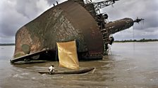 A fisherman passes the wreck of an old ship off Greenville. Liberia is scattered with wrecks owing to the 14 year civil war.