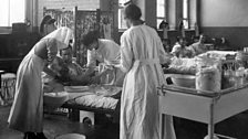 A nurse and two orderlies dressing a patient's wounds at the Endell Street Military Hospital