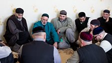 Chechen men sit on the floor as they wait for the ritual to begin.