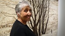 Artist Victoria Crowe next to the tapestry of her painting Large Tree Group