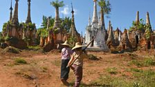 Woman walk to work past the surreal backdrop of She Indein Pagoda near Inle Lake